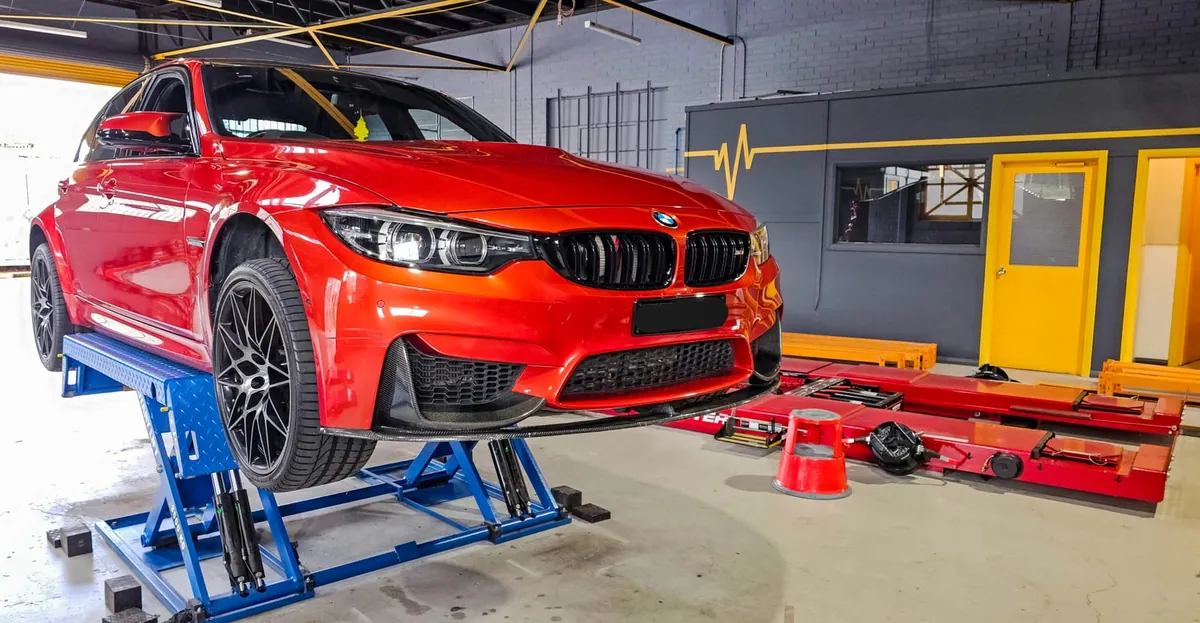 Red BMW M-series on the wheel-alignment hoist at Tyre Doctors
