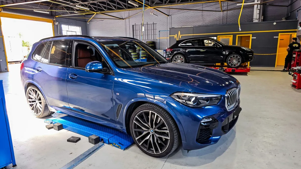 Blue BMW X5 on the hoist for tyres and wheel alignment