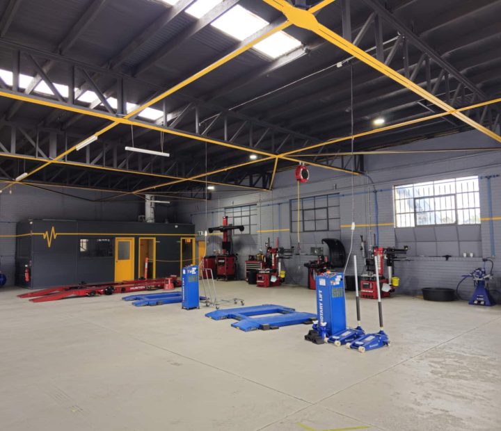 Interior of a tyre workshop with various equipment including lifts and tools arranged on the floor.