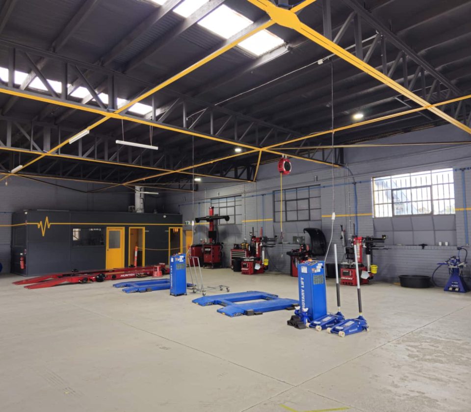 Interior of a tyre workshop with various equipment including lifts and tools arranged on the floor.